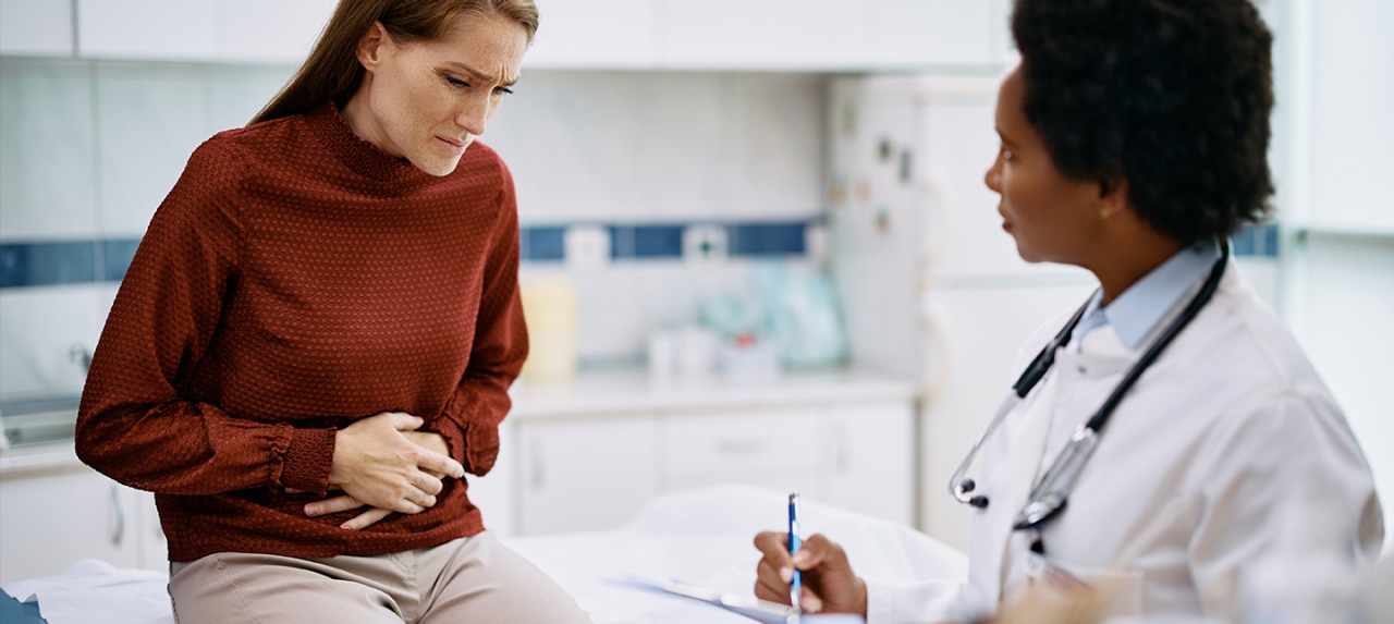 Young female patient experiencing abdominal pain at doctor's office