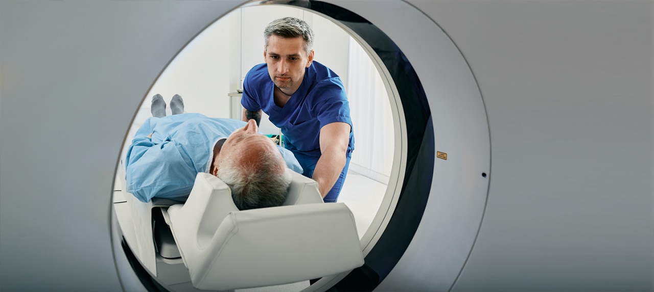 Male nurse helping to send elderly patient through MRI