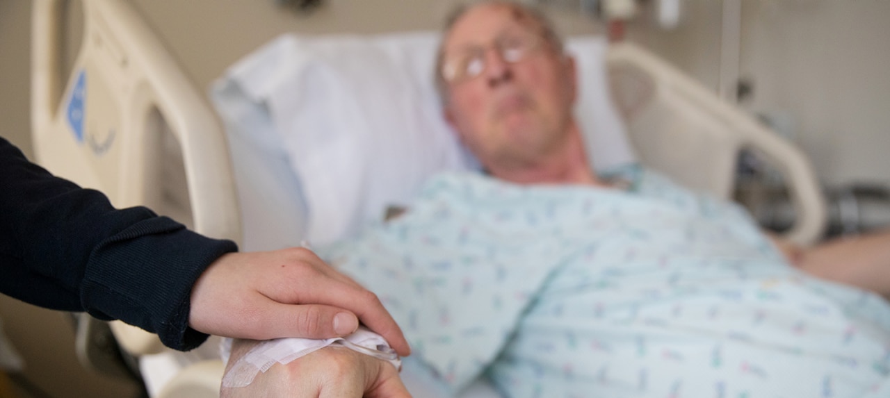 Elderly patient in recovery from surgery holding hands