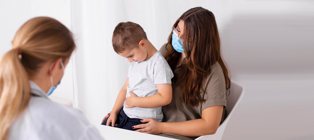 Young boy hernia patient at doctor's office with mom