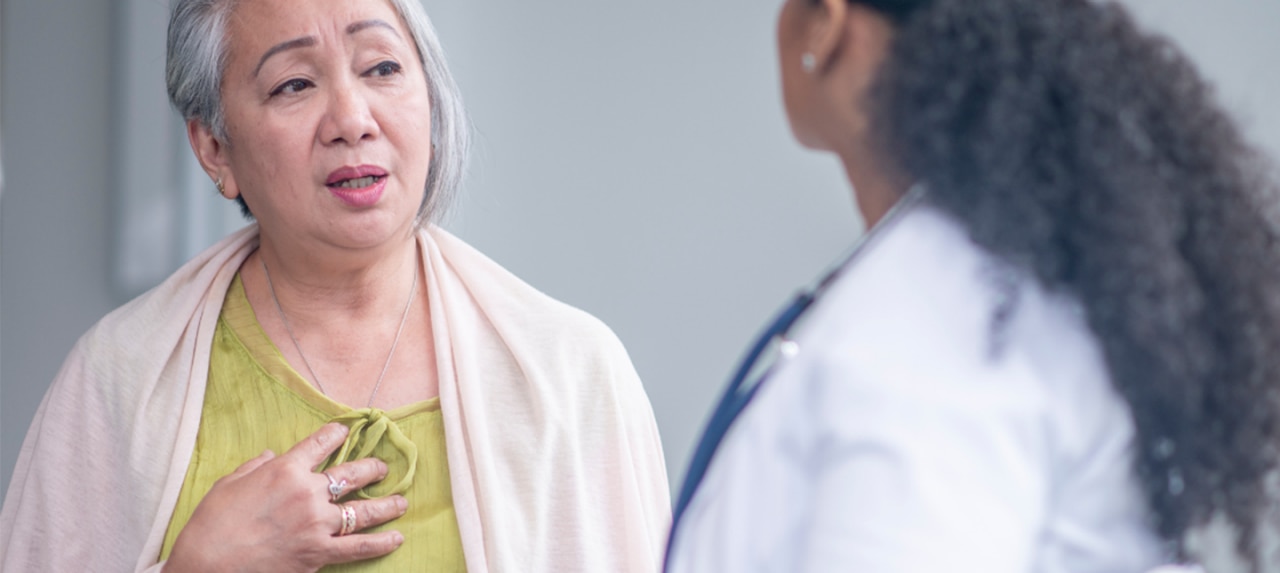 Elderly Asian female patient with a hiatal hernia speaking to a healthcare provider
