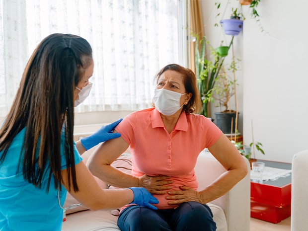 Female patient holding abdomen in pain consulting with nurse