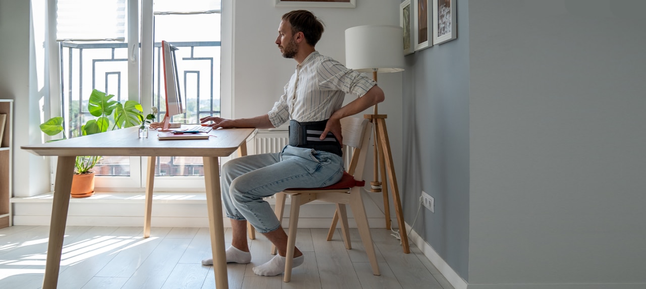 Man working from home wearing a hernia belt sitting down