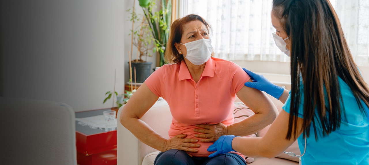 Female patient holding abdomen in pain consulting with nurse